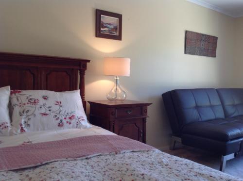 a bedroom with a bed and a blue chair at The Cook Cottage in Canberra