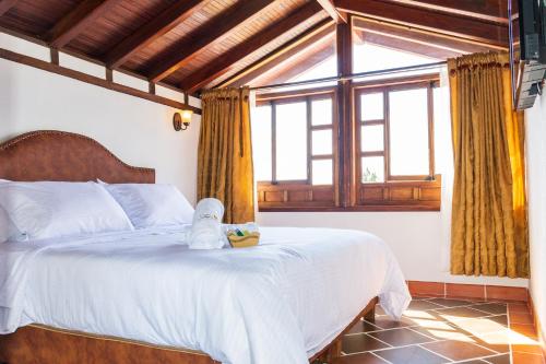 a bedroom with a bed with a stuffed animal on it at HOTEL ENCANTO COLONIAL in Villa de Leyva