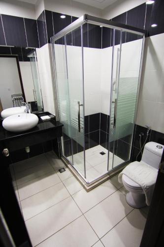 a bathroom with a shower and a toilet and a sink at Putatan Platinum Hotel in Kota Kinabalu