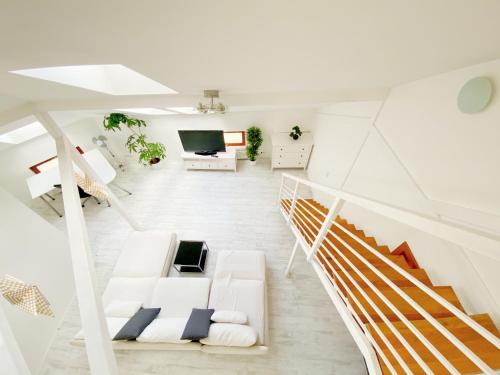 un soggiorno bianco con divano bianco e scale di Loft with Rooftop and Garage a Budapest