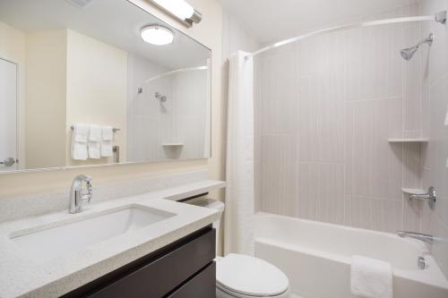 a white bathroom with a sink and a toilet at Candlewood Suites Dickinson, an IHG Hotel in Dickinson