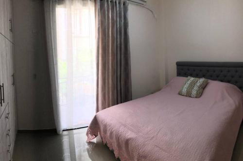 a bedroom with a bed with a pink blanket and a window at Loutraki Vibes Apartments in Loutraki