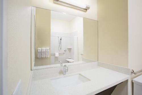 a white bathroom with a sink and a mirror at Candlewood Suites Dickinson by IHG in Dickinson