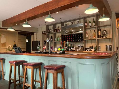 un bar con taburetes de madera en una habitación con botellas en The Dartmoor Inn at Lydford en Lydford