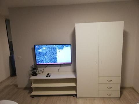 uma sala de estar com uma televisão e um armário branco em Vėjo 16 em Biržai