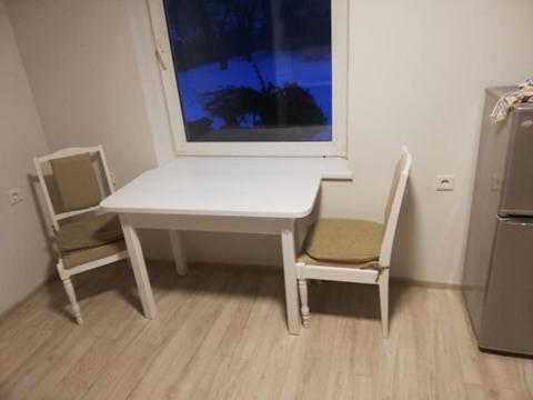 uma mesa branca e cadeiras num quarto com uma janela em Vėjo 16 em Biržai