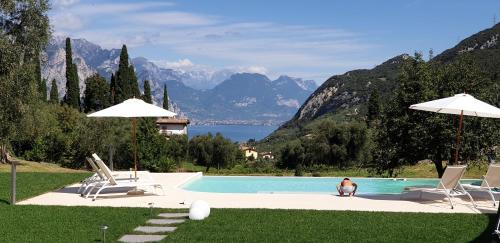 a swimming pool with two chairs and a man sitting next to it at Elle Ecoholiday in Malcesine