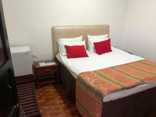 a bedroom with a bed with two red pillows at Hotel Camino Real Popayán Colombia in Popayan