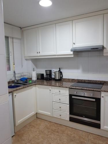 a kitchen with white cabinets and a stove top oven at Lovely 2 bedroom apartment close to Denia Castle. in Denia