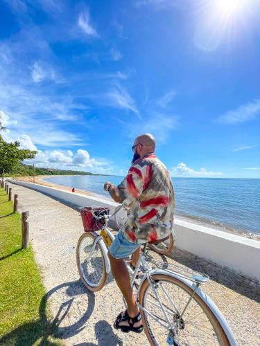 a man riding a bike next to the ocean at Best Western Shalimar Praia Hotel in Porto Seguro