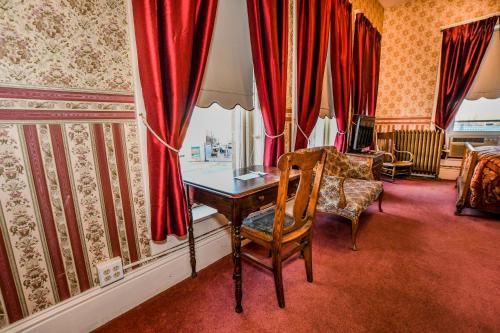 a room with a table and a chair and red curtains at Irma Hotel in Cody