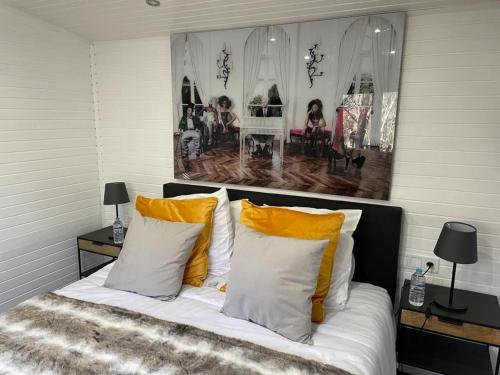 1 dormitorio con 1 cama con almohadas amarillas y blancas en Le Vert Logis en Lasne