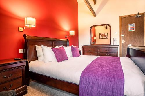 a bedroom with a large bed and a mirror at The Village Inn in Longframlington
