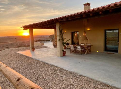 a house with a patio with the sunset in the background at Monte da Aparica in Galeguinha Grande