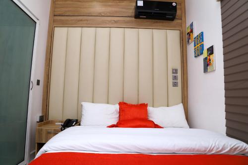 a bed with a red pillow on top of it at GAZANIA CLASSIC SUITE, RHODABODE APT. in Abuja