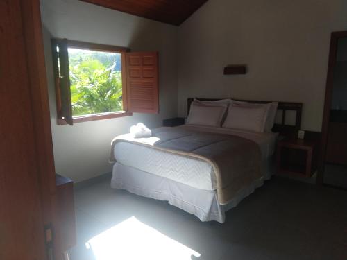 a bedroom with a large bed with a window at Pousada Flor Nativa in Brejetuba