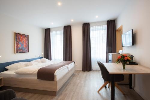 a bedroom with a large bed and a desk at CAESARO Hotel & Pizzeria - 20 Jahre Familienunternehmen in Hagen