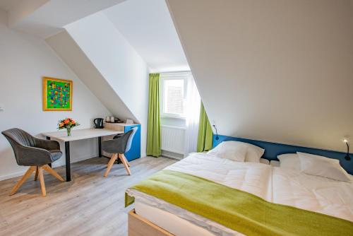 1 dormitorio con 1 cama y escritorio con sillas en CAESARO Hotel & Pizzeria - 20 Jahre Familienunternehmen, en Hagen