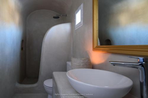 a bathroom with a sink and a toilet and a mirror at Aghios Artemios Traditional Houses in Imerovigli