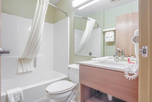 Microtel Inn & Suites by Wyndham Gulf Shores في غولف شورز: حمام مع مرحاض ومغسلة ومرآة