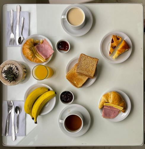 a white table topped with plates of breakfast foods and coffee at Posada de los Poetas Hotel Boutique in San Lorenzo