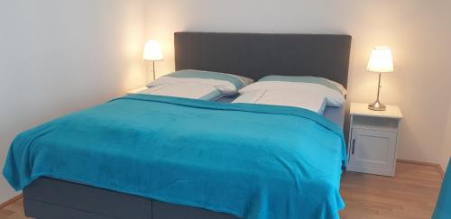 um quarto com uma cama grande e um cobertor azul em Exquisit Apartment Simmering em Viena