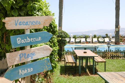 a sign in front of a pool with a table and chairs at Hôtel Rembrandt in Tangier