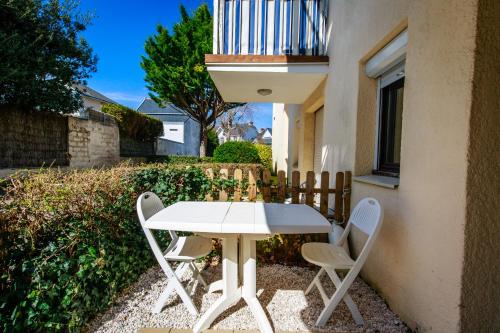 une table et des chaises blanches à côté d'un bâtiment dans l'établissement Appartement plage Benoit, 80m de la mer, jardinet, à La Baule