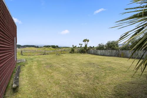 a yard with a fence and a grass field at Tranquilo - Waikawa Beach Holiday Home in Manakau