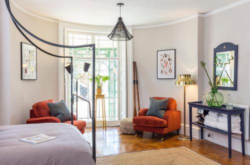 a bedroom with a bed and two chairs and a mirror at The State Room at Seafield House in Emsworth