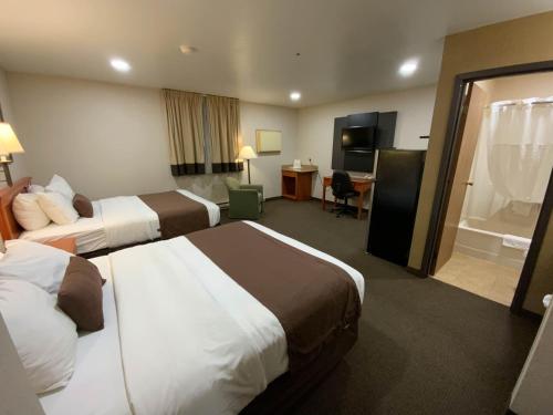 a hotel room with two beds and a bathroom at Studio 6 - Minot, ND in Minot