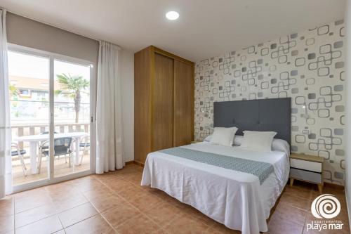 a bedroom with a bed and a balcony with a table at Apartamentos Turísticos Playa Mar I in Montalvo