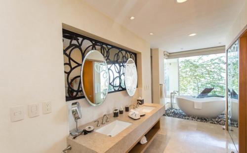 a bathroom with a tub and a large mirror at Suites at Garza Blanca Preserve Resort & Spa in Puerto Vallarta