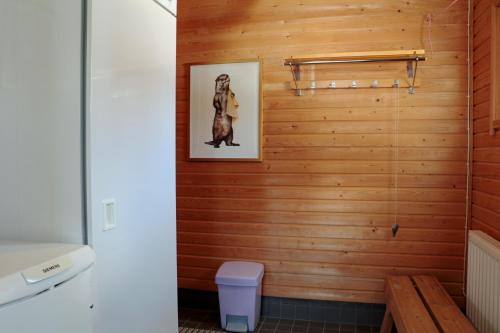 a bathroom with a wooden wall with a picture of a dog at TaloYlläs, Huonemajoitus in Äkäslompolo