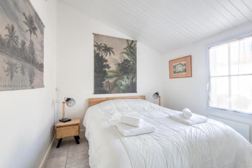 een witte slaapkamer met een bed met twee handdoeken erop bij Appartement Arôme in Saint-Martin-de-Ré