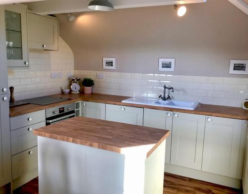 una cocina con armarios blancos y fregadero en Hill Cottage en Weston-super-Mare