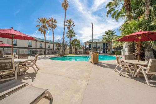 a resort pool with tables and chairs and palm trees at Motel 6-Laredo, TX - North I-35 in Laredo