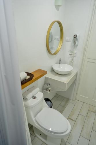 a white bathroom with a toilet and a sink at Hotel Casa Turquesa in Flores