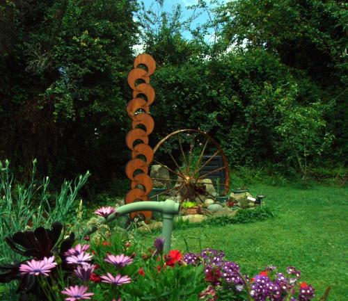 a garden with a waterwheel in the grass with flowers at The Tuai Suite Waikaremoana in Tuai