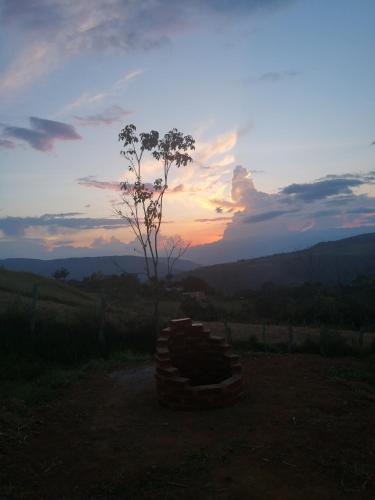 a sunset with a tree and a stack of logs at Villa Namaste, Cabaña Namaste 1 in Curití
