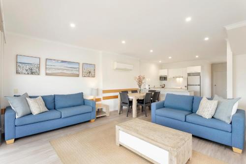 a living room with two blue couches and a table at Captains Cove Resort - Absolute Waterfront Apartments in Paynesville