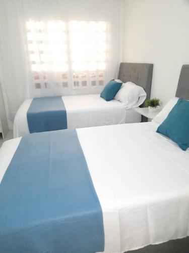 two beds with blue and white sheets in a room at Tita’s Airport Hotel in Cartagena de Indias