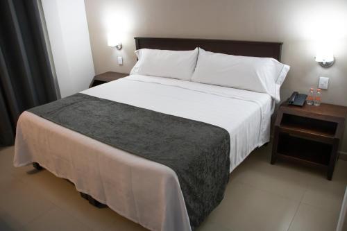 a bedroom with a large white bed with a night stand at Hotel Las Pergolas in Guadalajara