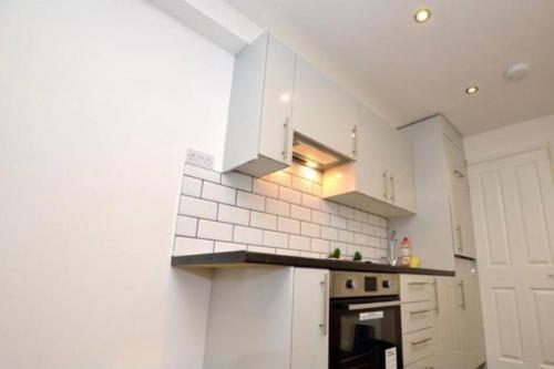 a kitchen with white cabinets and a stove at Small Cosy Studio In Plaistow. East London in London