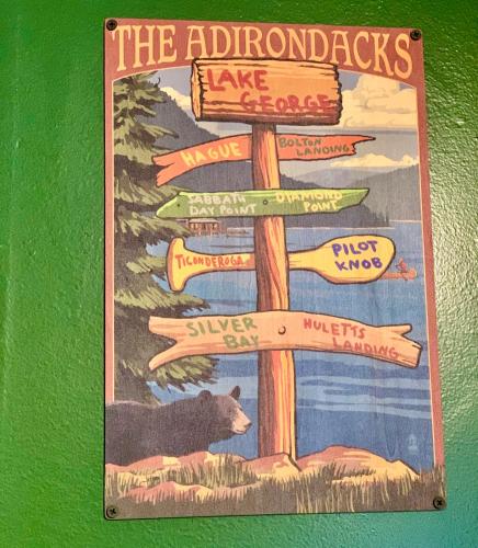 a wooden sign with a sign for the adirondacks have a bear at Motel Montreal in Lake George