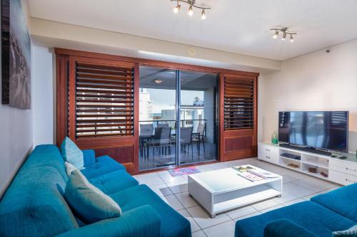 a living room with a blue couch and a television at The Waterford Prestige Apartments in Caloundra