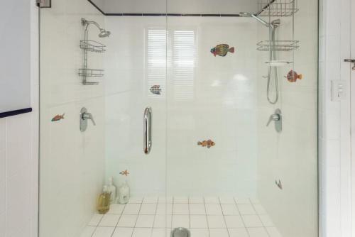 a shower with a glass door in a bathroom at Waterfront 2-bed cottage, Karaka Bays in Wellington