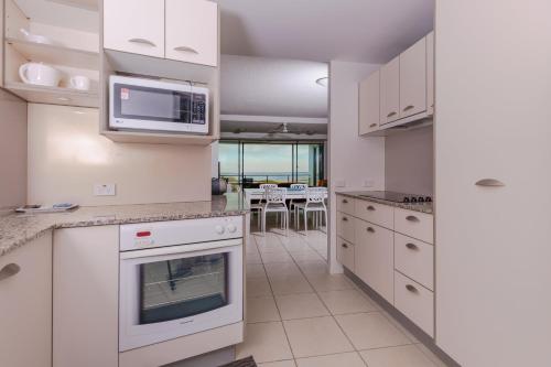 a kitchen with white cabinets and a microwave at The Waterford Prestige Apartments in Caloundra