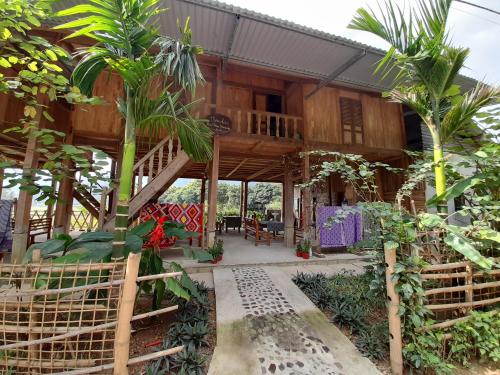 a house with palm trees in front of it at Meadow Mai Chau Homestay in Mai Chau