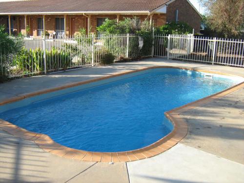 a swimming pool with blue water in a yard at Highway Inn Motel in Hay